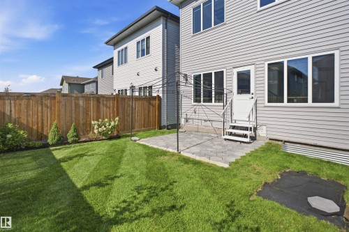 Expansive backyard featuring a manicured lawn, a wood privacy fence, and a paver patio - 2027 13 Avenue Nw, Edmonton, AB 