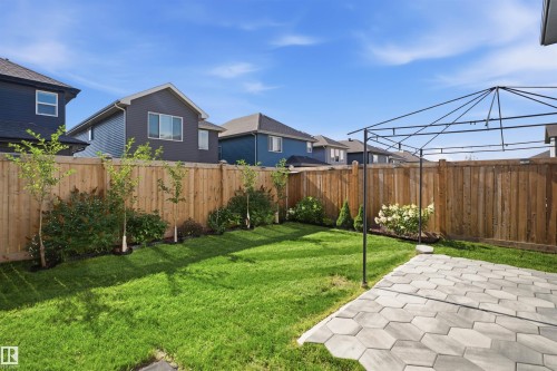 Manicured lawn with a wooden privacy fence, mature landscaping, and a paver patio - 2027 13 Avenue Nw, Edmonton, AB 