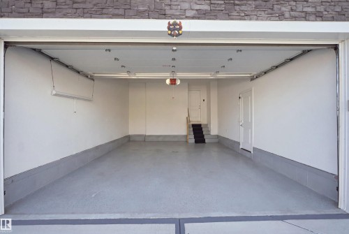 Spacious garage with light gray flooring, white painted walls, white door, and built-in overhead lighting - 2027 13 Avenue Nw, Edmonton, AB 