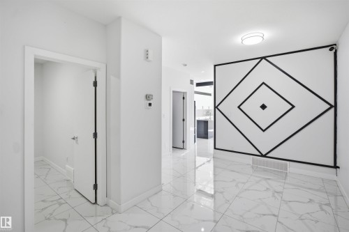 White walls with a black geometric accent, white tile flooring, and a flush-mount ceiling light - 2027 13 Avenue Nw, Edmonton, AB 