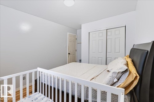 Wood-finish flooring with a white six-panel door and sliding closet doors - 12919 135 Avenue Nw, Edmonton, AB 