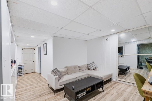 Wood-finish flooring, drop ceiling with recessed lighting, mirrored sliding doors, and white walls - 12919 135 Avenue Nw, Edmonton, AB 