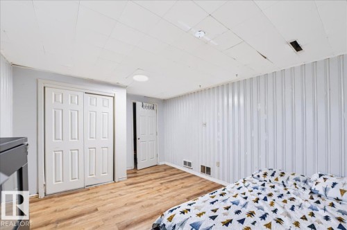 Wood-finish flooring, white paneled walls, white paneled bi-fold closet doors, and a white six-panel door - 12919 135 Avenue Nw, Edmonton, AB 