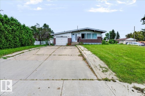 Front exterior featuring a concrete driveway, attached garage, and a manicured lawn - 12919 135 Avenue Nw, Edmonton, AB 