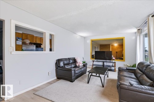 Light wood-finish flooring, white walls, and a large window providing natural illumination - 12919 135 Avenue Nw, Edmonton, AB 