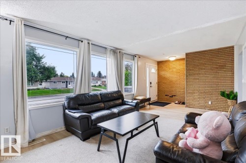 Expansive window array, brick accent wall, white entry door with glass inserts, overhead flush-mount lighting, and light wood-finish flooring - 12919 135 Avenue Nw, Edmonton, AB 