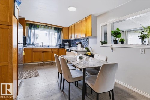 Kitchen featuring wood cabinetry, tiled flooring, dark blue tiled backsplash, and recessed lighting - 12919 135 Avenue Nw, Edmonton, AB 