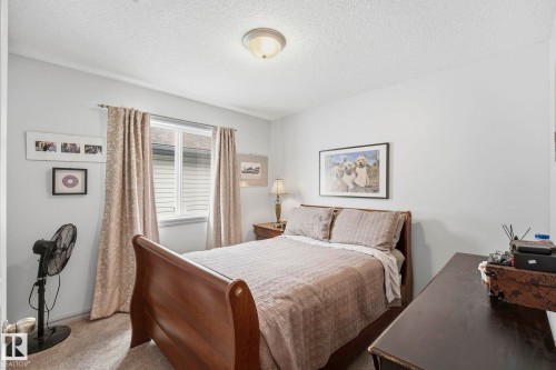 Recessed window with white blinds, wood-finish bed frame, and flush-mount ceiling light - 3231 28A Avenue Nw, Edmonton, AB 