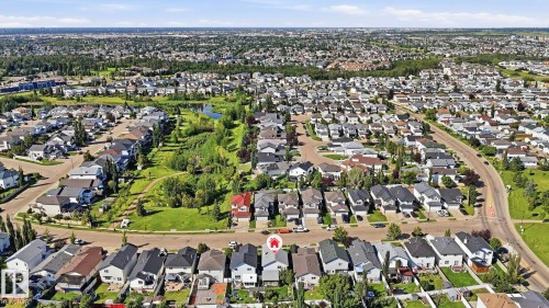 Residential neighborhood featuring a variety of single-family homes, mature trees, and a naturalized pond area - 3231 28A Avenue Nw, Edmonton, AB 