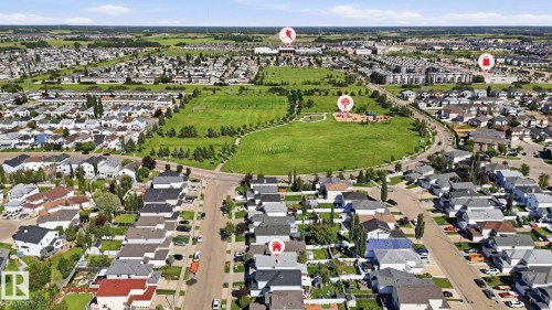 Aerial perspective of a residential neighborhood featuring detached homes, a large central green space, and visible roadways - 3231 28A Avenue Nw, Edmonton, AB 