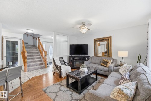 Open-concept living space with wood-finish flooring, a built-in electric fireplace, and a ceiling fan with integrated lighting - 3231 28A Avenue Nw, Edmonton, AB 