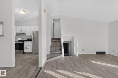 Spacious living area featuring wood-finish flooring and a vaulted ceiling - 3722 34A Avenue Nw, Edmonton, AB - Indoor