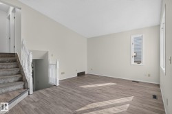 Spacious room featuring wood-finish flooring, light-toned walls, and a window providing natural illumination - 