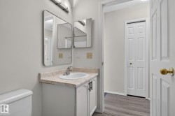 Bathroom vanity featuring a white cabinet with black hardware, a light-toned countertop, and an integrated sink - 