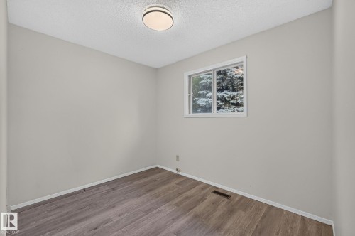 Interior room featuring light gray walls, wood-finish flooring, white baseboards, and a single window with white trim - 3722 34A Avenue Nw, Edmonton, AB - Indoor Photo Showing Other Room