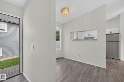 Open concept dining space featuring wood-finish flooring, a pass-through window to the kitchen, and a decorative ceiling light fixture - 