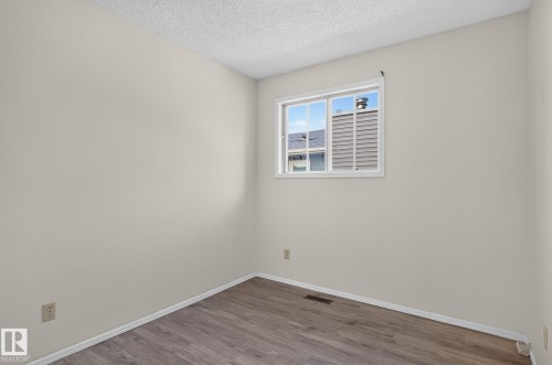 Neutral tone walls with wood-finish flooring, white baseboards, and a white window frame - 3722 34A Avenue Nw, Edmonton, AB - Indoor Photo Showing Other Room