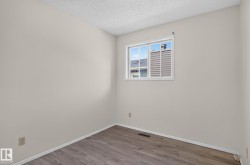 Neutral tone walls with wood-finish flooring, white baseboards, and a white window frame - 