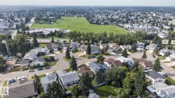Residential neighborhood featuring detached homes on tree-lined streets, with a large park space visible in the background - 