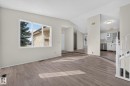 Spacious living area featuring wood-finish flooring, a large multi-pane window, and a crisp white color palette - 3722 34A Avenue Nw, Edmonton, AB  - Indoor Photo Showing Other Room 