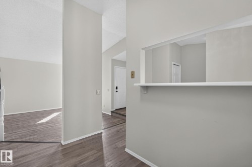 Interior doorway featuring wood-finish flooring, light grey wall paint, white baseboards, and a white interior door - 3722 34A Avenue Nw, Edmonton, AB - Indoor Photo Showing Other Room