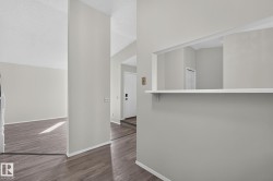 Interior doorway featuring wood-finish flooring, light grey wall paint, white baseboards, and a white interior door - 