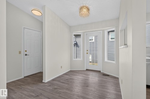 Dining area featuring wood-finish flooring, a crystal chandelier, and a bay window with a glass-paned door - 3722 34A Avenue Nw, Edmonton, AB - Indoor Photo Showing Other Room