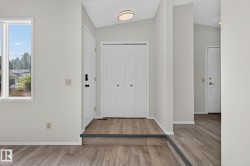 Entryway featuring wood-finish flooring, light neutral wall paint, and a white front door with dark hardware - 