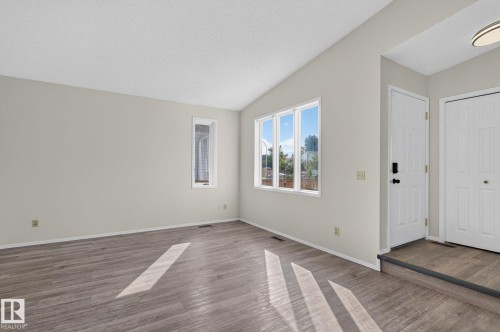 Living area featuring wood-finish flooring, vaulted ceiling, and neutral wall tones - 3722 34A Avenue Nw, Edmonton, AB - Indoor Photo Showing Other Room