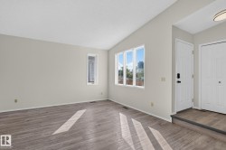 Living area featuring wood-finish flooring, vaulted ceiling, and neutral wall tones - 
