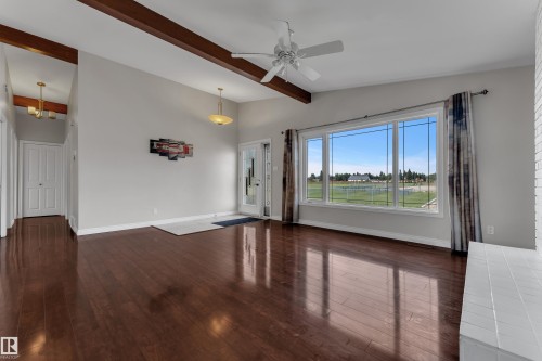 Wood-finish flooring, exposed ceiling beams, a ceiling fan, and a large multi-pane window - 8803 68A Street Nw, Edmonton, AB 