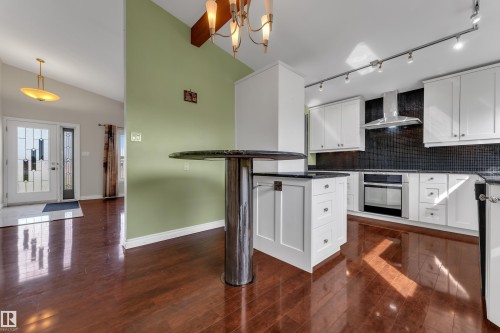 Kitchen featuring white cabinetry, dark countertops, a dark mosaic tile backsplash, and stainless steel appliances - 8803 68A Street Nw, Edmonton, AB 
