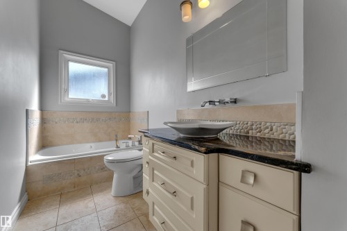 Cream-finished vanity with a dark countertop, vessel sink, and an extensive mirror - 8803 68A Street Nw, Edmonton, AB 