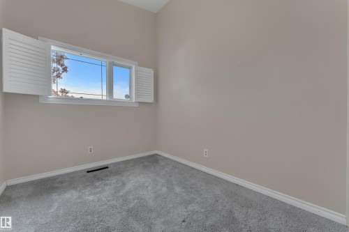 Window with white plantation shutters, neutral wall paint, and gray carpet - 8803 68A Street Nw, Edmonton, AB 