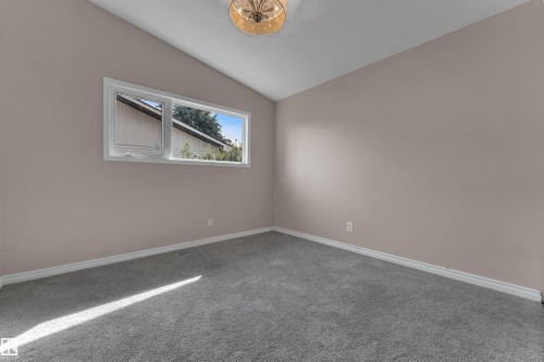 Neutral wall paint, sloped ceiling, horizontal window, ceiling-mounted light fixture, and grey carpet flooring - 8803 68A Street Nw, Edmonton, AB 