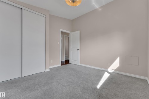 Wall-to-wall carpeting with light-colored walls, white trim, and a built-in closet with sliding doors - 8803 68A Street Nw, Edmonton, AB 