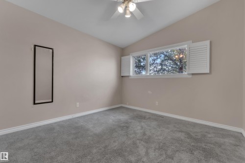 Vaulted ceiling, light neutral wall color, gray carpeting, horizontal window with white shutters, and a ceiling fan with light fixture - 8803 68A Street Nw, Edmonton, AB 