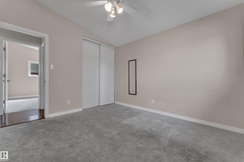 Room featuring sloped ceilings, a ceiling fan with integrated lighting, gray carpet flooring, and a closet with sliding doors - 8803 68A Street Nw, Edmonton, AB 