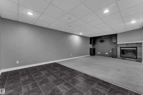 Recessed lighting, drop ceiling, and a fireplace with a stone-tile surround - 8803 68A Street Nw, Edmonton, AB 