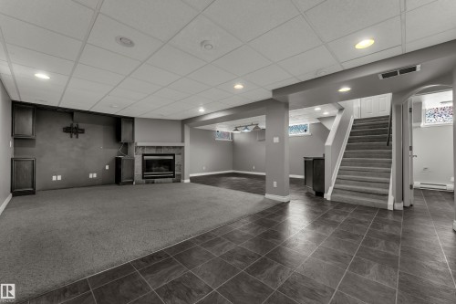 Recessed lighting, tile flooring, carpeted area, fireplace with stone surround, and built-in cabinetry - 8803 68A Street Nw, Edmonton, AB 