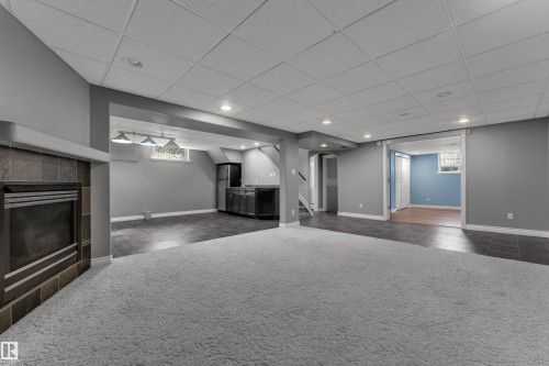 Carpeted flooring, recessed lighting, fireplace with tile surround, built-in cabinetry, and tile flooring - 8803 68A Street Nw, Edmonton, AB 