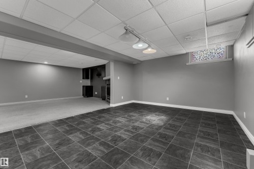 Expansive finished basement featuring tile flooring, track lighting, drop ceiling, and a built-in cabinet with a fireplace - 8803 68A Street Nw, Edmonton, AB 