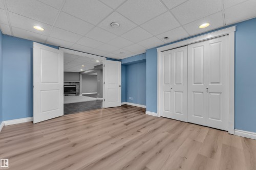 Wood-finish flooring, drop ceiling with recessed lighting, double bi-fold closet doors, and French doors - 8803 68A Street Nw, Edmonton, AB 