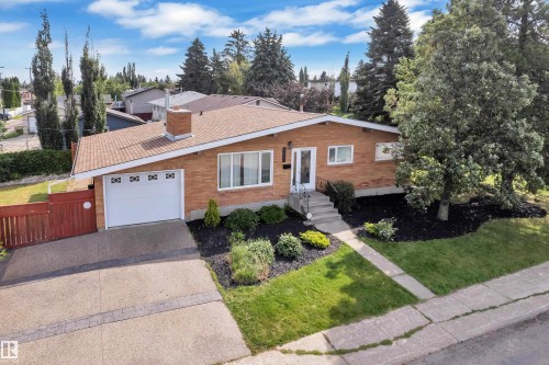 Brick exterior, attached garage, concrete driveway, mature trees, landscaped front yard - 8803 68A Street Nw, Edmonton, AB 
