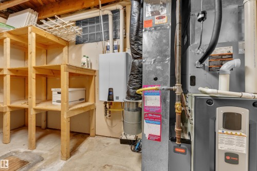 Utility area featuring a water heater, furnace, and wood shelving - 8803 68A Street Nw, Edmonton, AB 