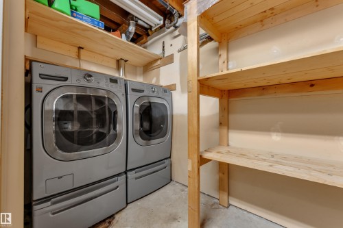 Laundry area featuring a side-by-side washer and dryer, built-in wooden shelving, and concrete flooring - 8803 68A Street Nw, Edmonton, AB 