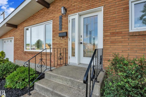 Brick exterior, concrete steps, wrought iron railing, decorative front door with transom window, and an attached garage - 8803 68A Street Nw, Edmonton, AB 
