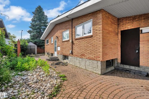 Brick exterior with white-framed windows, a patterned paver pathway, and a gravel bed - 8803 68A Street Nw, Edmonton, AB 