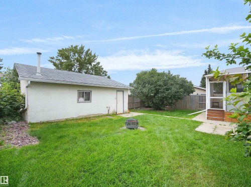 Expansive lawn, detached garage with shingle roof, screened porch with wood-finish steps, concrete patio, and perimeter fencing - 7435 32 Avenue Nw, Edmonton, AB 