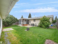 Expansive backyard featuring a screened-in porch with wood-finish decking, a concrete patio, and a privacy fence - 
